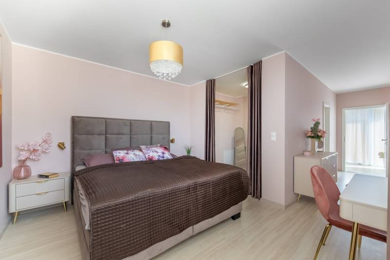 Schlafzimmer im Einfamilienhaus mit großem Bett, Kleiderschrank und Boden mit Holzdekor.