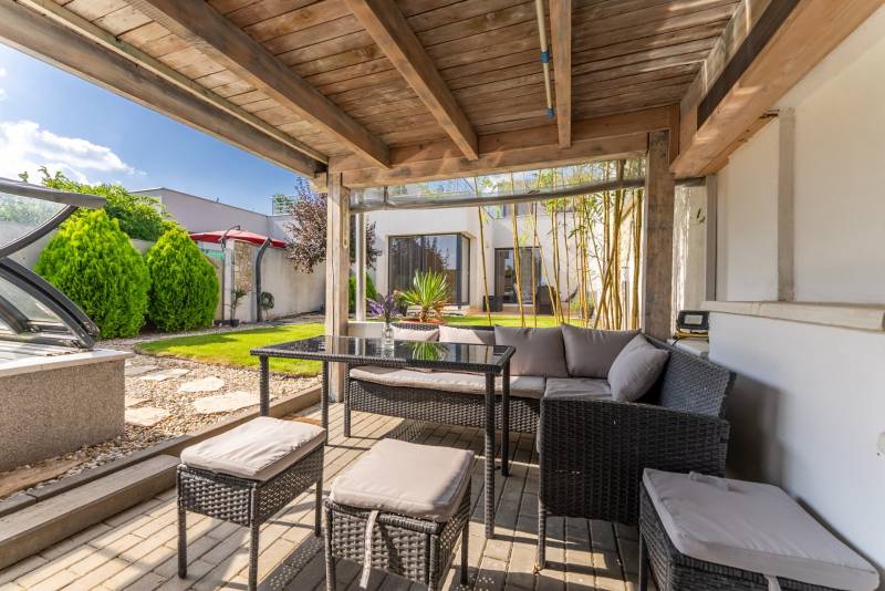 Die Terrasse des Einfamilienhauses in der Jazdecká-Straße in Trnava mit Rattanmöbeln und einem versteckten Pool.