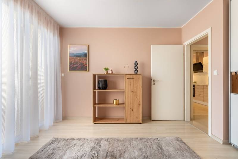 Innenraum eines Einfamilienhauses mit Holzboden, Schrank und Vorhängen.