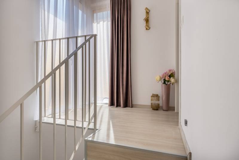 Innenraum eines Einfamilienhauses mit Holzboden, Vorhängen und dekorativer Beleuchtung.