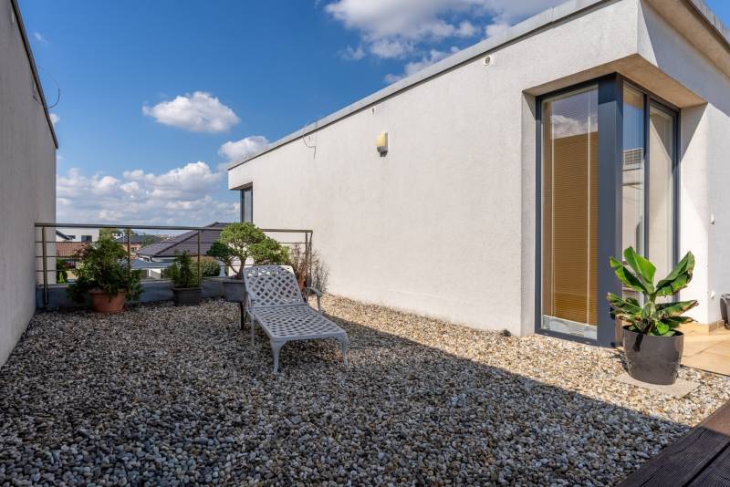 Die Terrasse des Einfamilienhauses in der Jazdecká-Straße in Trnava mit Grünflächen und einer Liege.