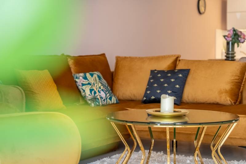 Einfamilienhaus mit Sofa, Tisch mit Kerze und dekorativen Kissen.