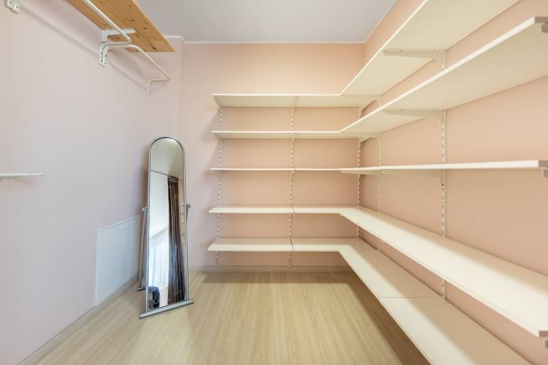 Ein Kleiderschrank im Einfamilienhaus mit Regalen, einem Standspiegel und einem Boden mit Holzdekor.