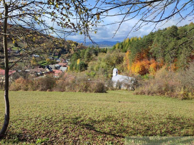 Eine Kirche umgeben von herbstlicher Natur in Záhrady, Hlboké nad Váhom mit Blick auf die Berge.