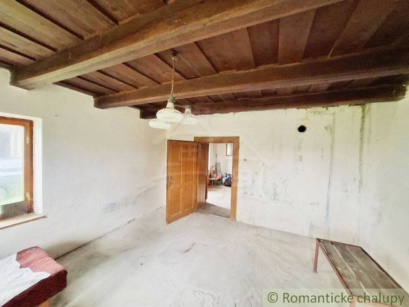 Innenraum eines Einfamilienhauses mit Holzdecke, weißen Wänden und einfacher Einrichtung.