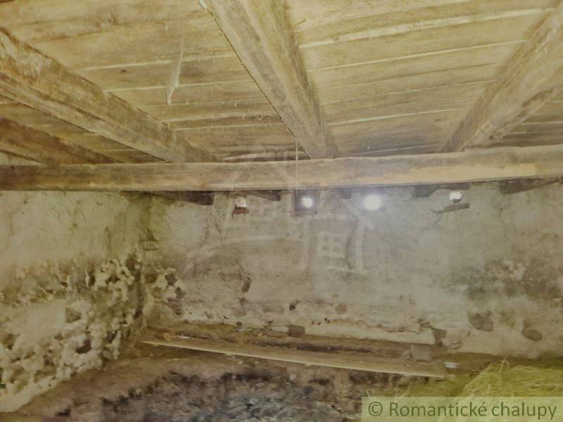 Innenraum eines Einfamilienhauses mit Holzbalkendecke und Steinwänden.