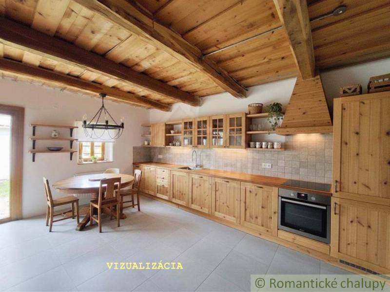 Eine Küche in einem Einfamilienhaus mit einer mit Holz verkleideten Decke, einem Tisch und Schränken.