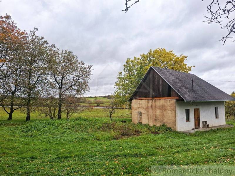 Ein Einfamilienhaus in Senohrad, umgeben von Bäumen und einem grasbewachsenen Grundstück unter einem bewölkten Himmel.