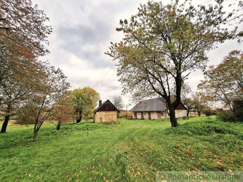 Ein weitläufiger Garten in Senohrad mit einem Einfamilienhaus und Bäumen auf einem grasbewachsenen Grundstück.