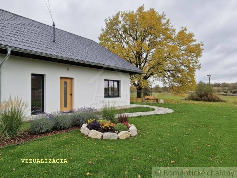 Ein Einfamilienhaus in Senohrad mit weißer Fassade, gepflegtem Garten und einem großen Baum.