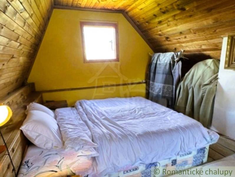 Ein Schlafzimmer in einer Hütte mit einem Bett, einem Dachfenster und Holzelementen.