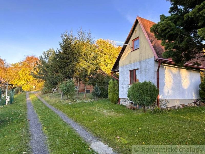 Eine Hütte in Sološnica an der Straße, umgeben von Bäumen und Rasen im Herbst.