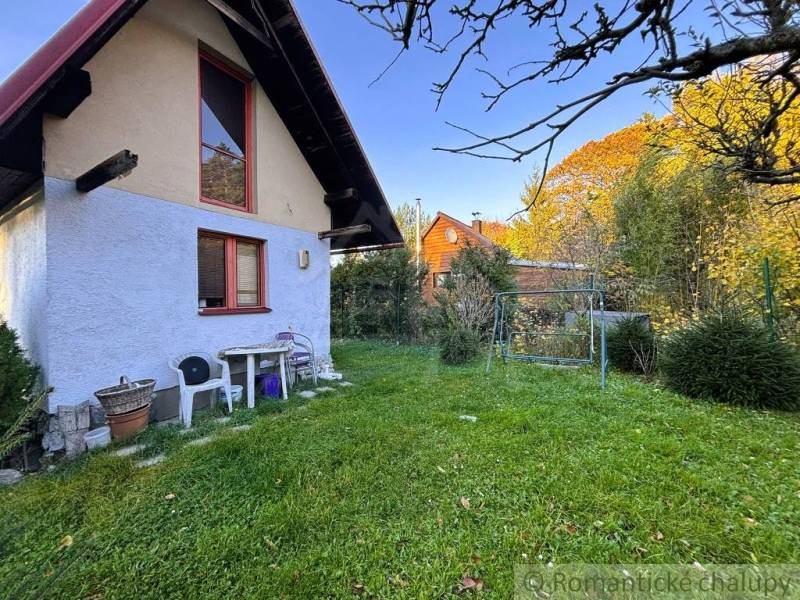 Das Äußere der Hütte in Sološnica, umgeben von grünem Rasen und Bäumen.