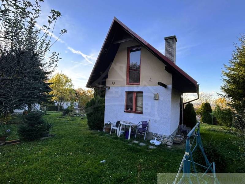 Eine Hütte in Sološnica mit einem gepflegten Garten, umgeben von Bäumen und klarem Himmel.