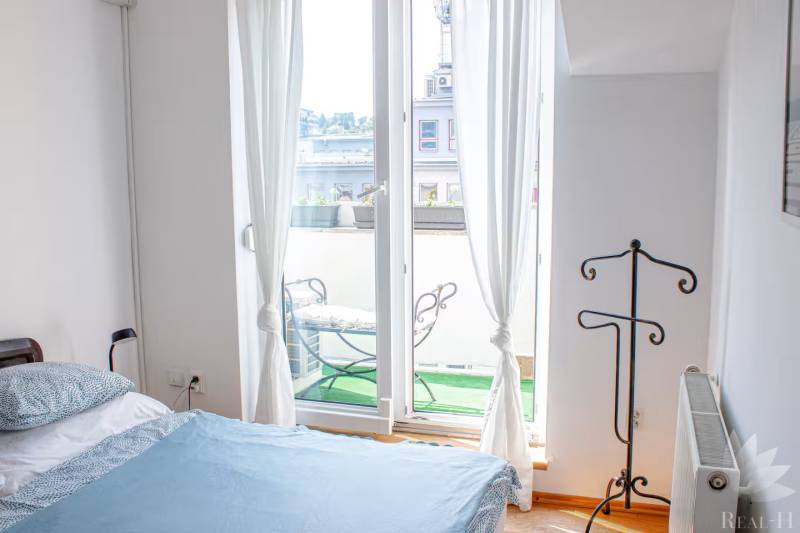 Schlafzimmer in einer 3-Zimmer-Wohnung mit Balkon und Blick nach draußen durch ein französisches Fenster.