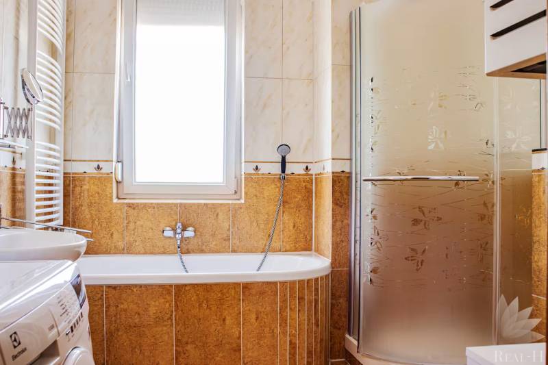 Badezimmer mit Badewanne, Dusche und Waschmaschine in einer 3-Zimmer-Wohnung.