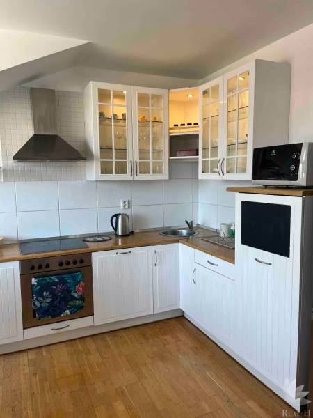 Küche in einer 3-Zimmer-Wohnung mit Holzboden, weißen Schränken und Stauraum.