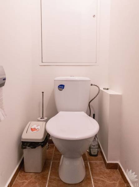 Badezimmer mit Toilette, Mülleimer und Holzboden in einer 2-Zimmer-Wohnung.