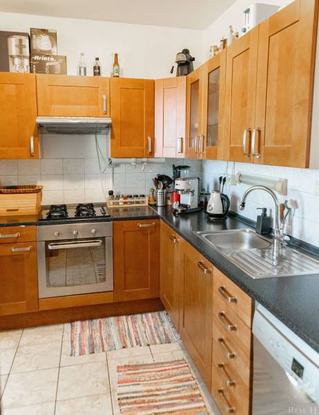 Küche in einer 2-Zimmer-Wohnung mit braunen Schränken, Herd und Geschirrspüler.