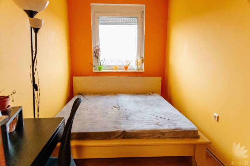 Schlafzimmer mit Bett, Schreibtisch und Fenster in einer 2-Zimmer-Wohnung.