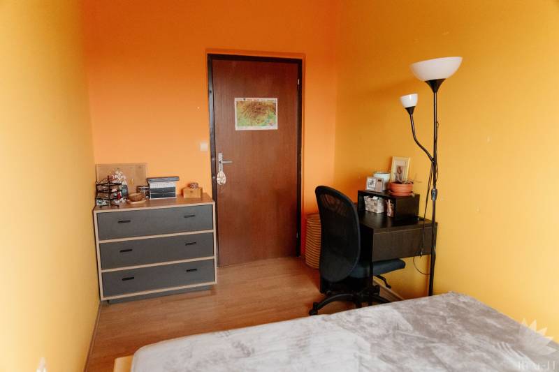 Ein Zimmer in einer 2-Zimmer-Wohnung mit orangefarbenen Wänden, einem Tisch und einem Regal.