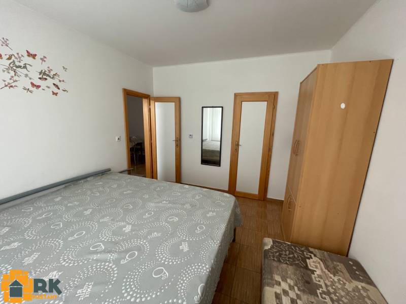 Ein Schlafzimmer mit Bett, Schrank und Spiegel in einem Einfamilienhaus mit Holzboden.