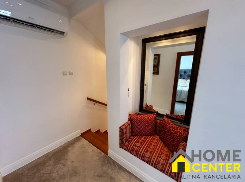 Das Einfamilienhaus zeigt eine Treppe mit Holzdekor, einen Spiegel und eine Sitzecke mit Kissen.