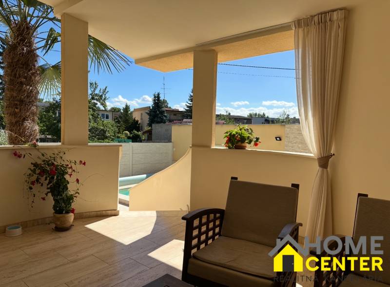 Die Terrasse des Einfamilienhauses in Komárno mit Sitzgelegenheit und Blick auf den Hof mit einer Palme.