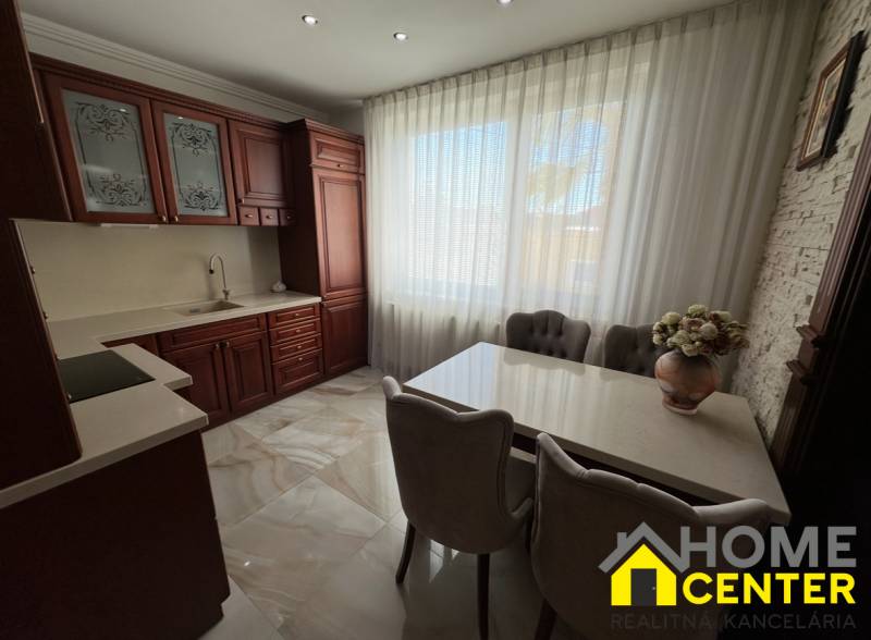 Küche mit dunklen Schränken, weißen Vorhängen und Blumendekoration in einem Einfamilienhaus.