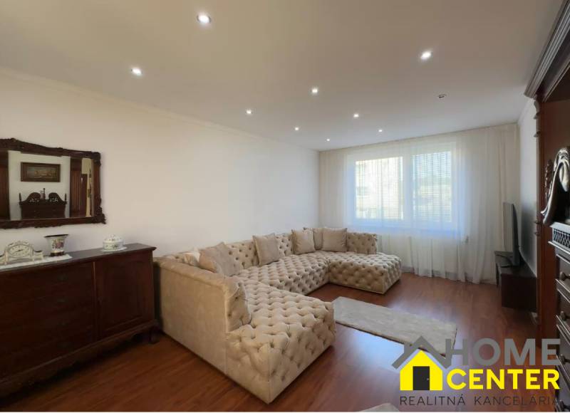 Wohnzimmer mit großem Sofa, Holzboden und antiken Möbeln.