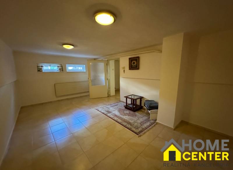 Innenraum eines Einfamilienhauses mit Fliesen, Teppich, kleinen Fenstern und einem einfachen Tisch.