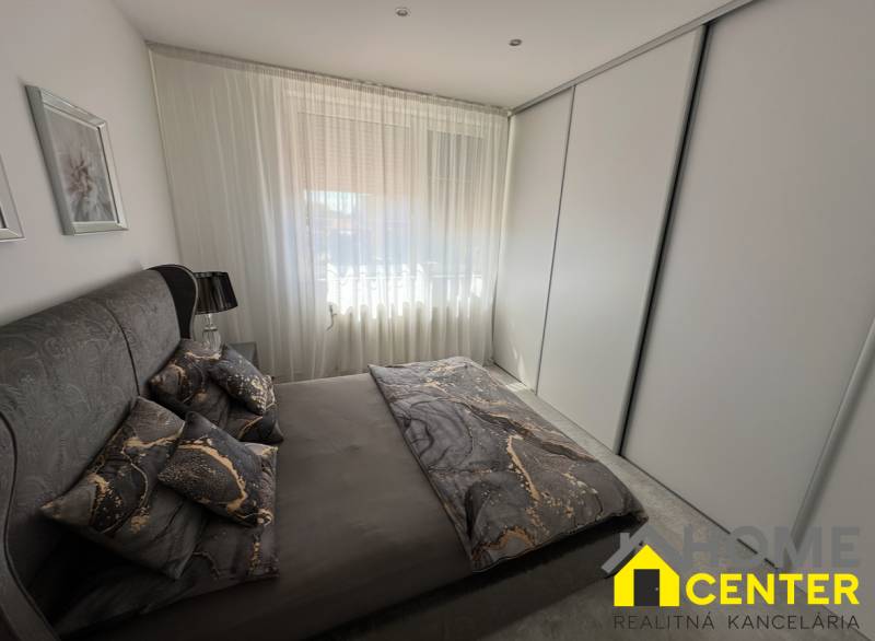 Ein Schlafzimmer in einem Einfamilienhaus mit dunkler Bettwäsche und einem großen Schrank.