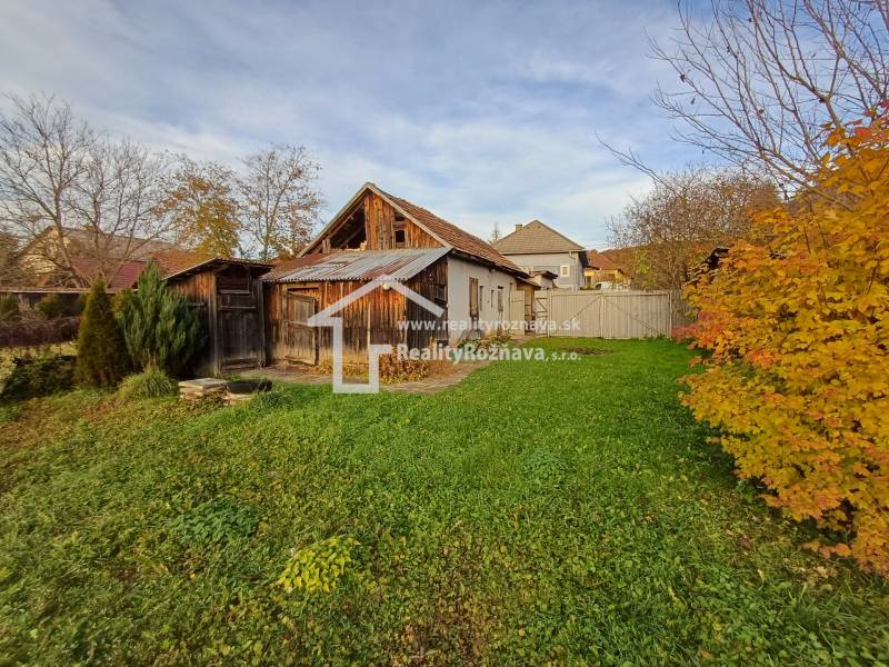 Ein Einfamilienhaus in Dlhá Ves mit Garten, Holzanbauten und herbstlicher Vegetation.