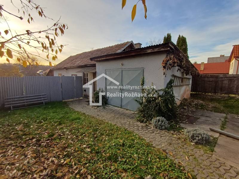 Ein Einfamilienhaus in Dlhá Ves mit einem Hof, einer Rasenfläche und einer Garage, umgeben von einem Zaun.