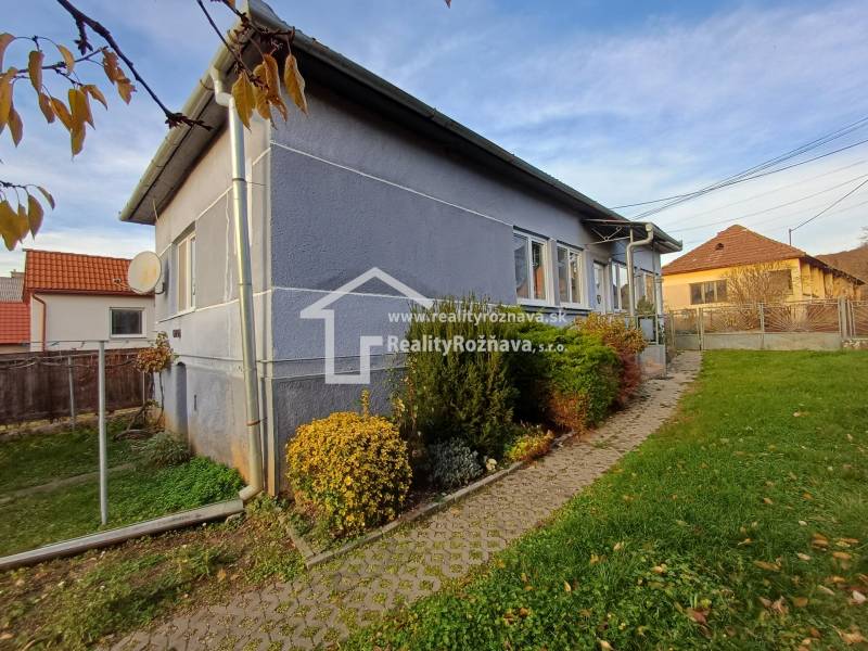 Ein Einfamilienhaus in Dlhá Ves, ein Garten mit Sträuchern, ein gepflasterter Weg zum Eingang.