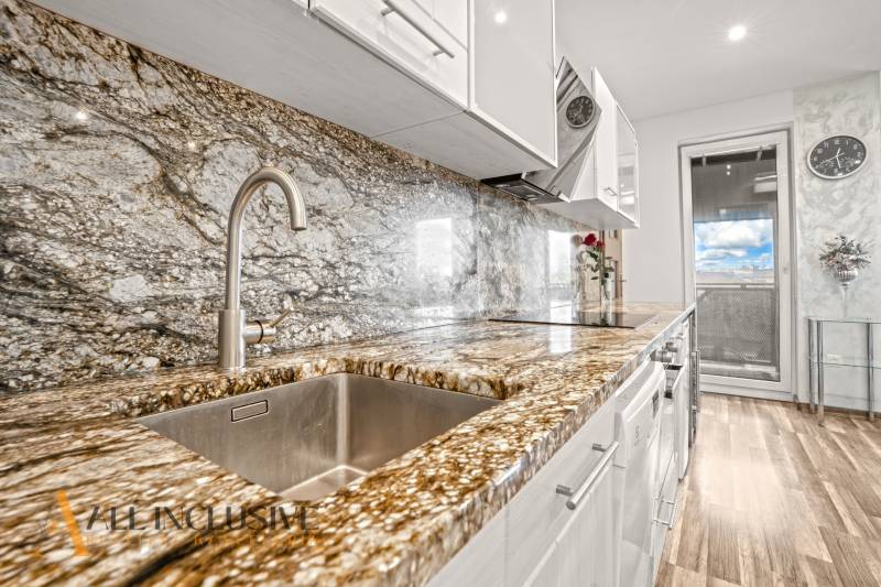 Küche mit Arbeitsplatte aus Stein und Bodenbelag in Holzoptik in einer 3-Zimmer-Wohnung.