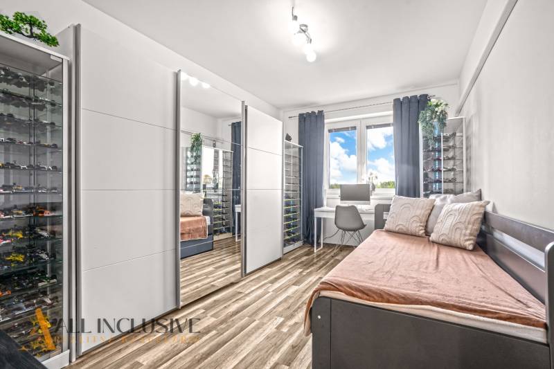 Ein Zimmer mit einem Spiegelschrank, einem Schreibtisch und einem Boden mit Holzdekor in einer 3-Zimmer-Wohnung.