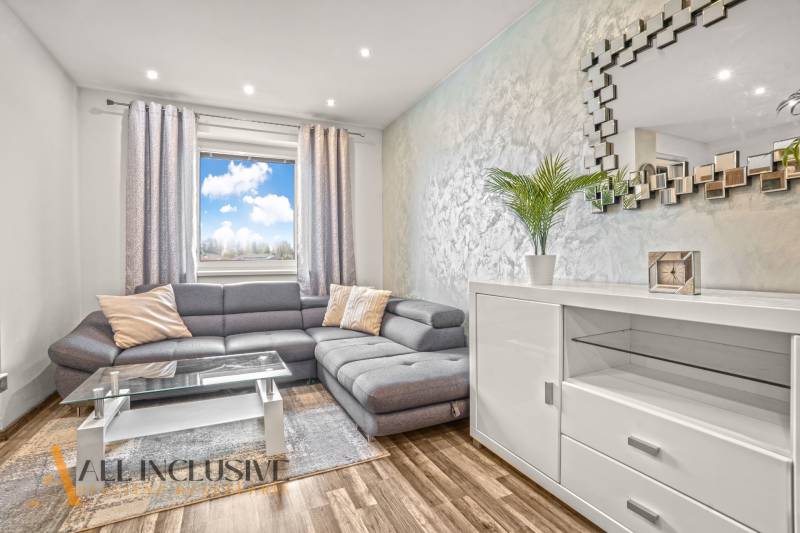 Wohnzimmer in einer 3-Zimmer-Wohnung mit einem bequemen Sofa und einem Boden in Holzoptik.