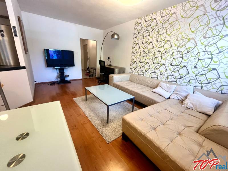 Wohnzimmer mit beigem Sofa und Fernseher in einer 3-Zimmer-Wohnung.