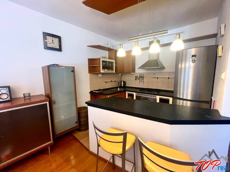 Küche in einer 3-Zimmer-Wohnung mit Bartresen, Metallstühlen und eleganten Lampen.