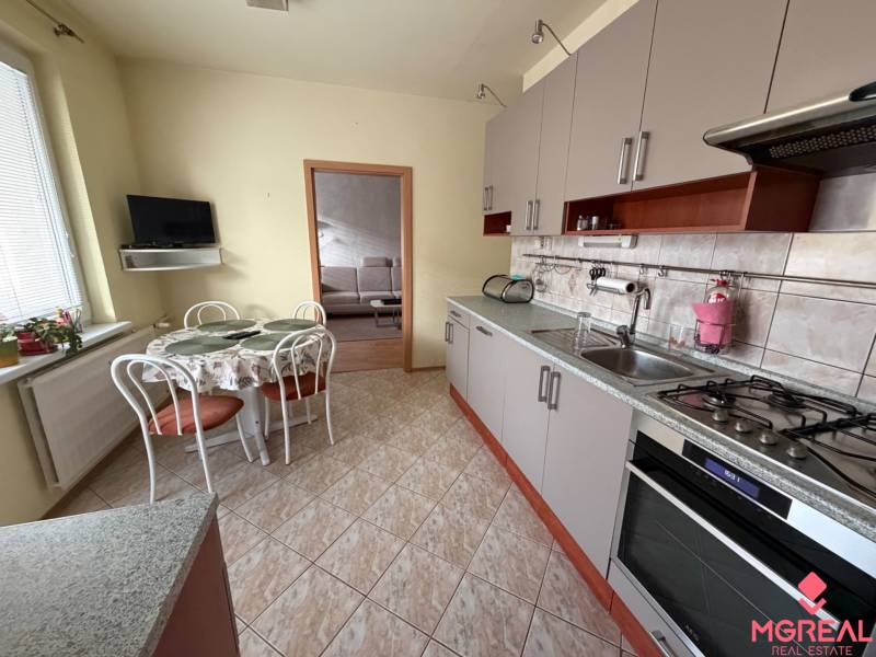 Küche in einer 3-Zimmer-Wohnung mit einer Eckküche, einem Tisch und einem Fernseher an der Wand.