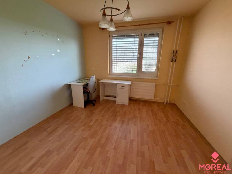 Ein Zimmer in einer 3-Zimmer-Wohnung mit einem Boden in Holzoptik und einem Schreibtisch.