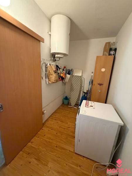 Waschküche in einer 3-Zimmer-Wohnung mit Boiler und Boden in Holzoptik.