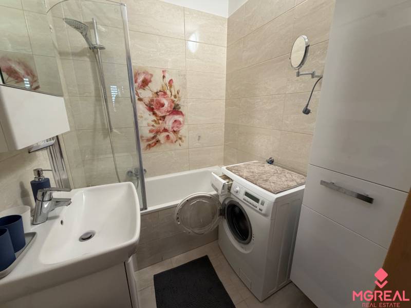 Badezimmer mit Blumendekoration in einer 3-Zimmer-Wohnung, Waschmaschine neben der Badewanne.