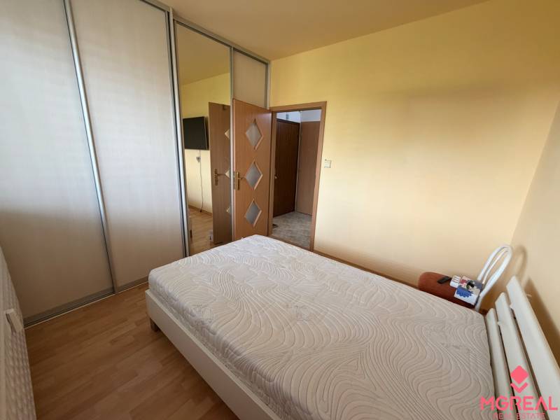 Schlafzimmer in einer 3-Zimmer-Wohnung mit Bett, Kleiderschränken und Boden in Holzdekor.