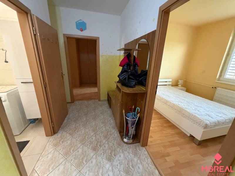 Flur in einer 3-Zimmer-Wohnung mit Fliesenboden, Zugang zum Badezimmer und Schlafzimmer mit Holzboden-Dekor.