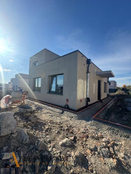 Ein Einfamilienhaus im Bau in Hubice ohne Geländeanpassung. Klarer Himmel und Sonnenlicht.