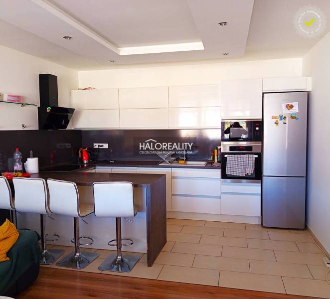 Küche in einer 3-Zimmer-Wohnung mit Bartresen, weißen Schränken und modernen Geräten.