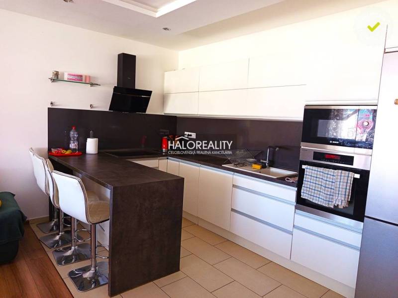 Eine Küche mit weißen Schränken und einer Bartheke in einer 3-Zimmer-Wohnung.