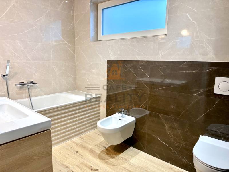 Badezimmer in einem Einfamilienhaus mit Badewanne, Waschbecken, Bidet und Boden mit Holzdekor.